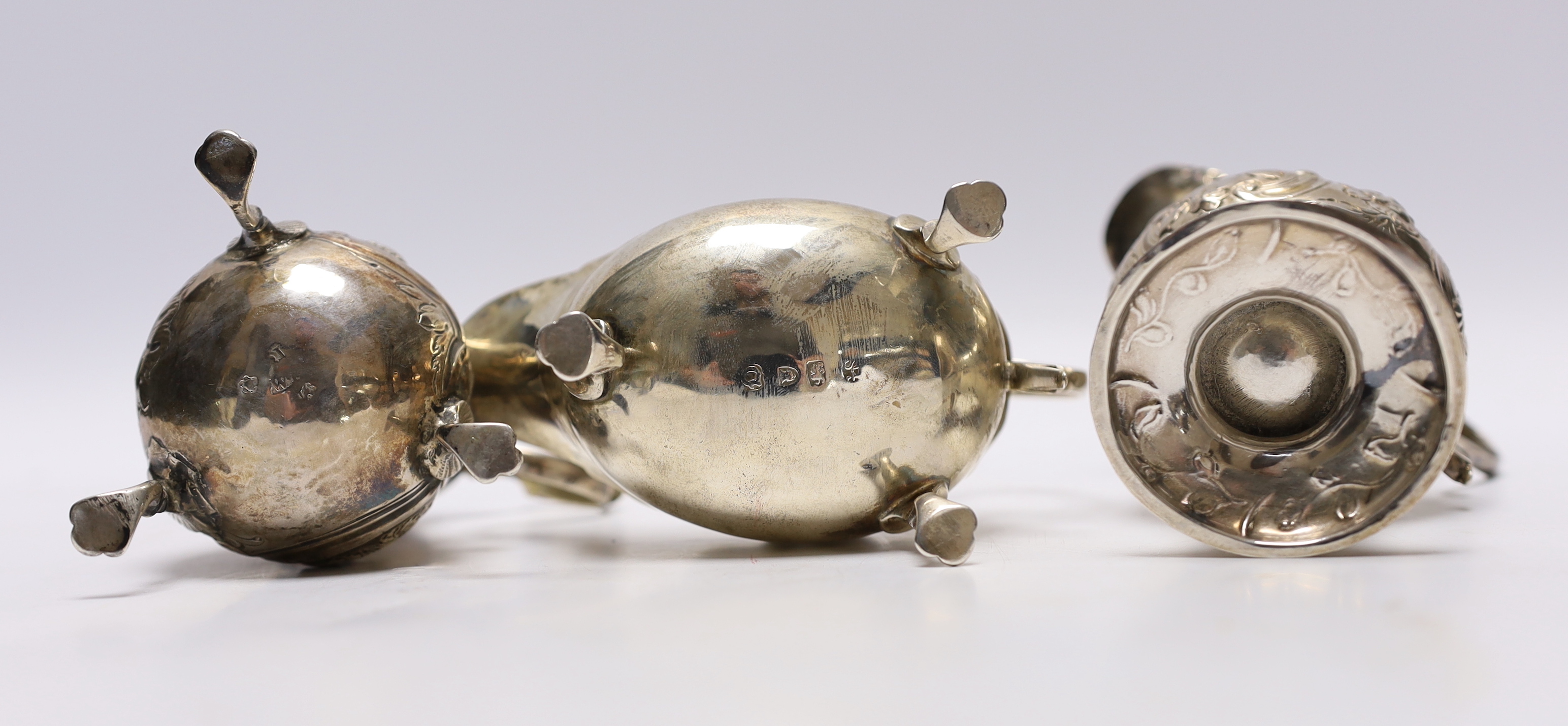 A late George II silver sauceboat with flying scroll handle, London, 1759 and two Georgian silver cream jugs, with later embossed decoration (a.f.)